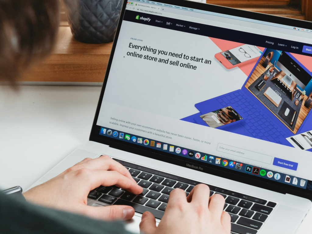 Create a Shopify account A man using a laptop and browsing through Shopify’s homepage.